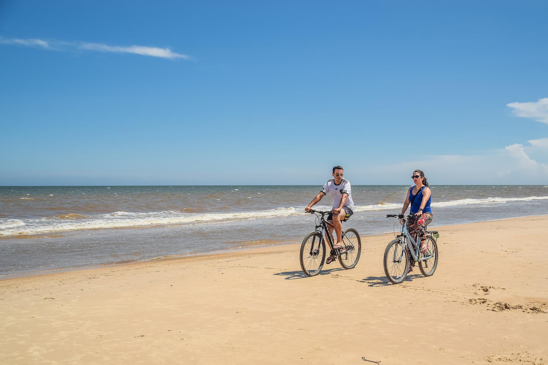 A couple exploring a bike trail on a beach.